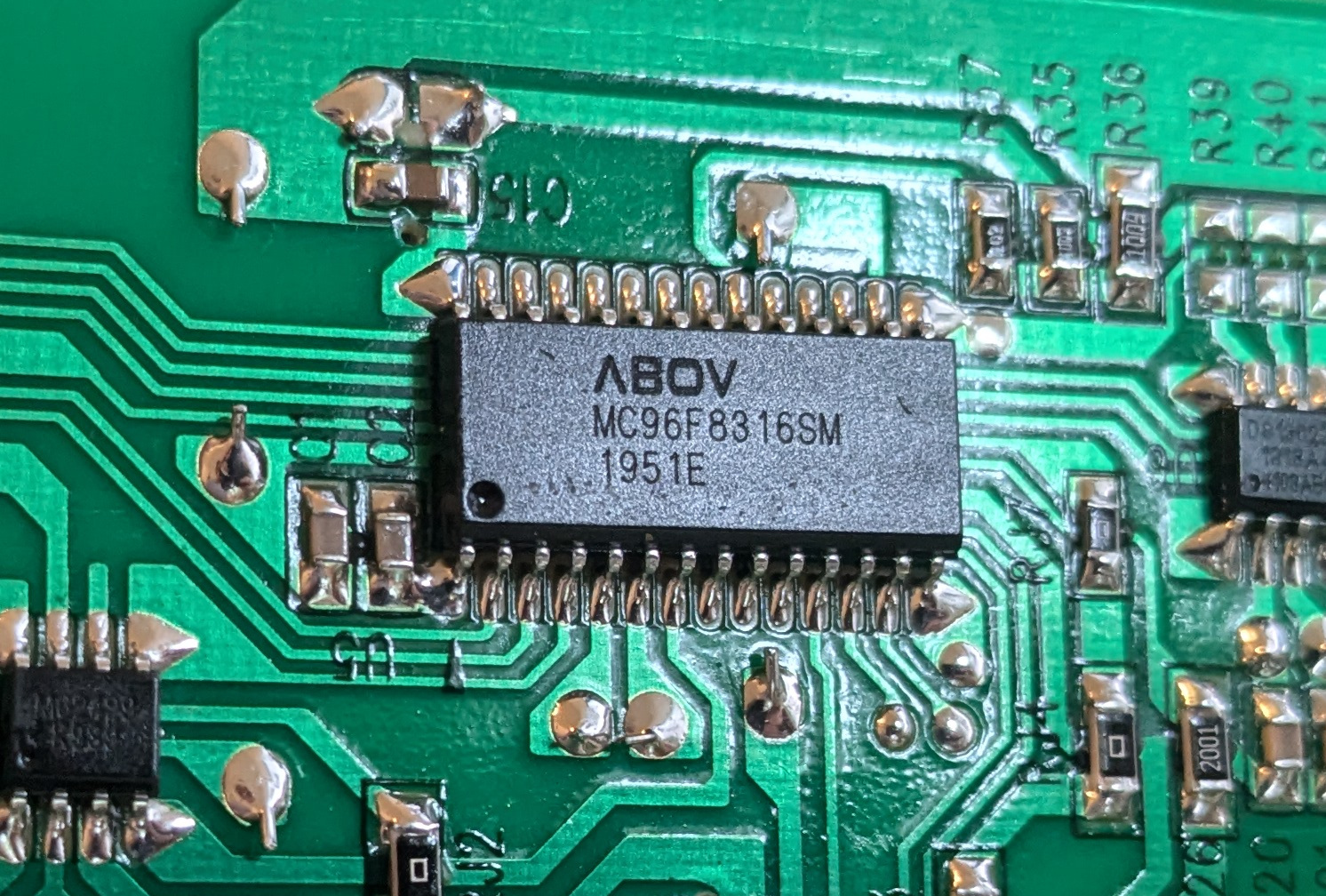 A close-up of a circuit board, centered on an integrated circuit labeled “ABOV MC96F8316SM 1951E”